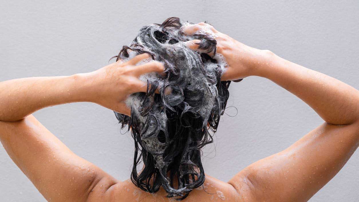 woman lathering her hair with shampoo